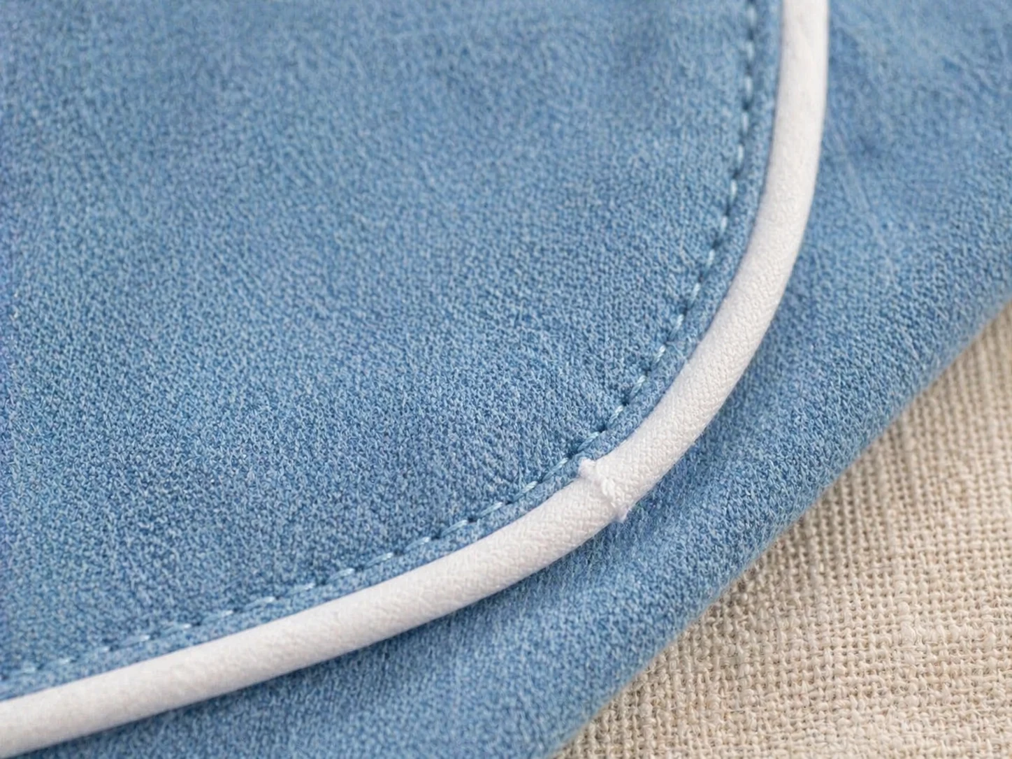 Macro do vivo branco fazendo a curva no chambray sky blue · pesponto firme · acabamento de bancada