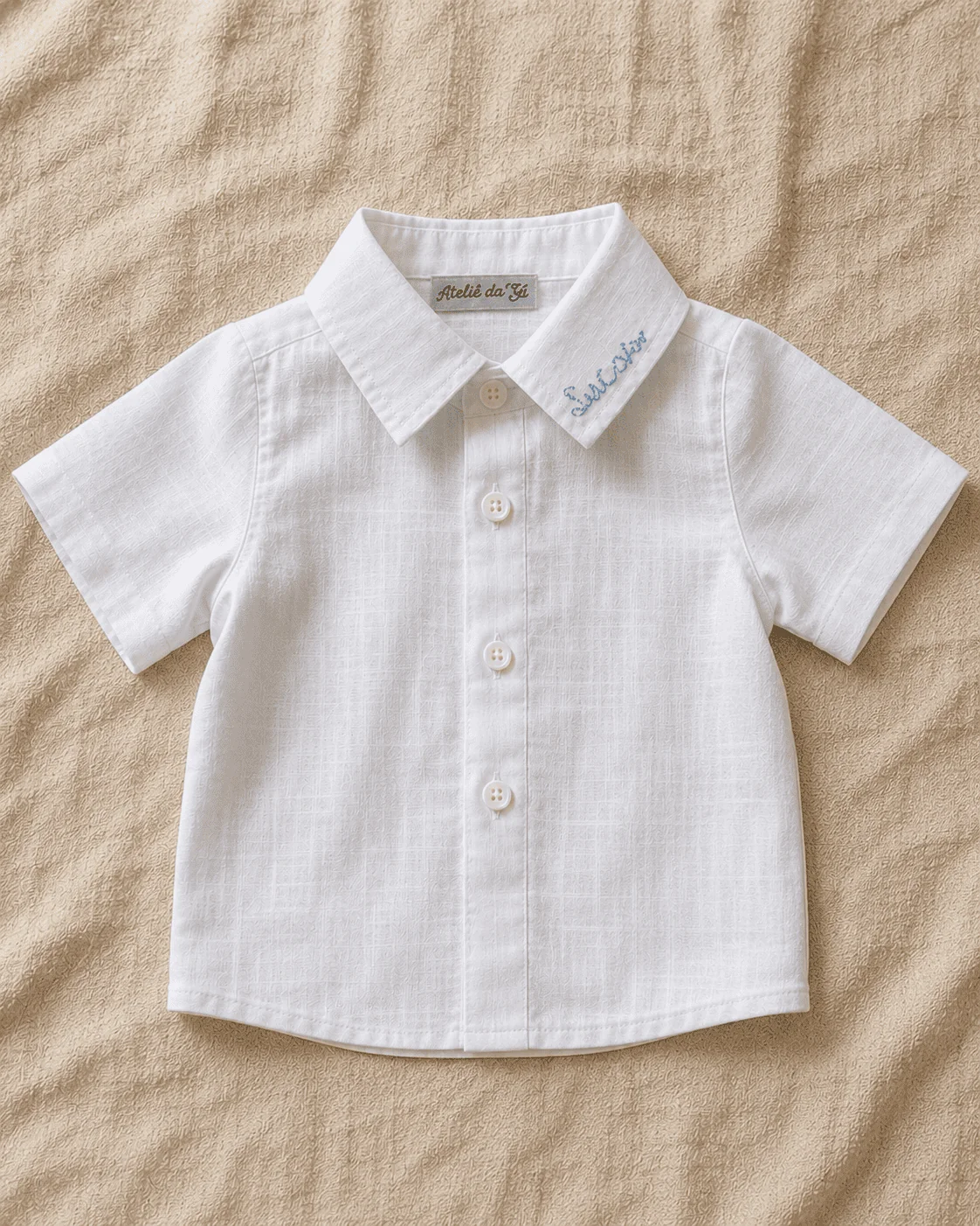 Camisa Social em linho branco · gola padre · 3 botões frontais · nome do menino bordado em script azul no colarinho · etiqueta Atelier da Gi